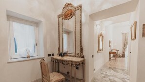 Una habitación con un espejo grande y ornamentado, un tocador con una silla y una ventana con vistas.