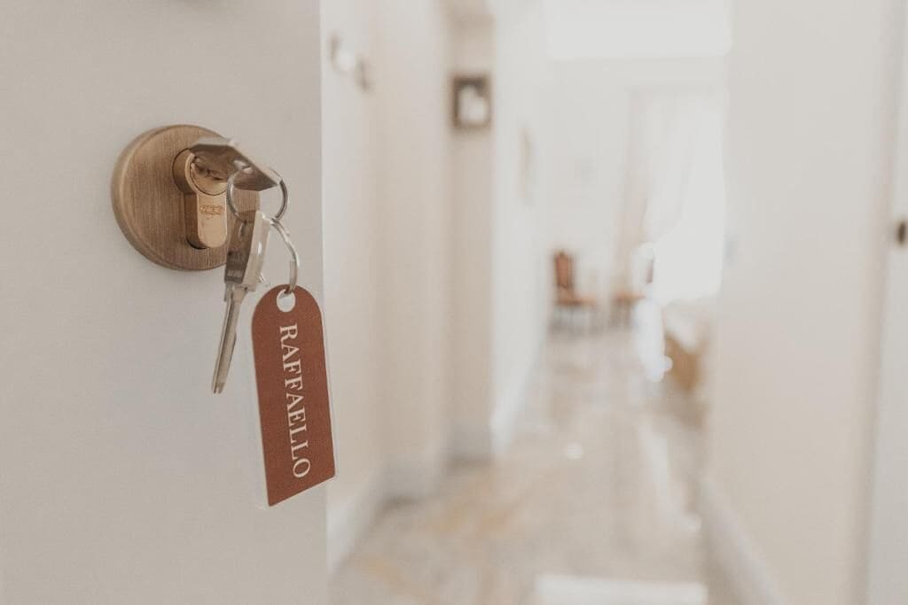 Puerta de una habitación de hotel con un llavero con la etiqueta 'RAFAELLO' y una llave.