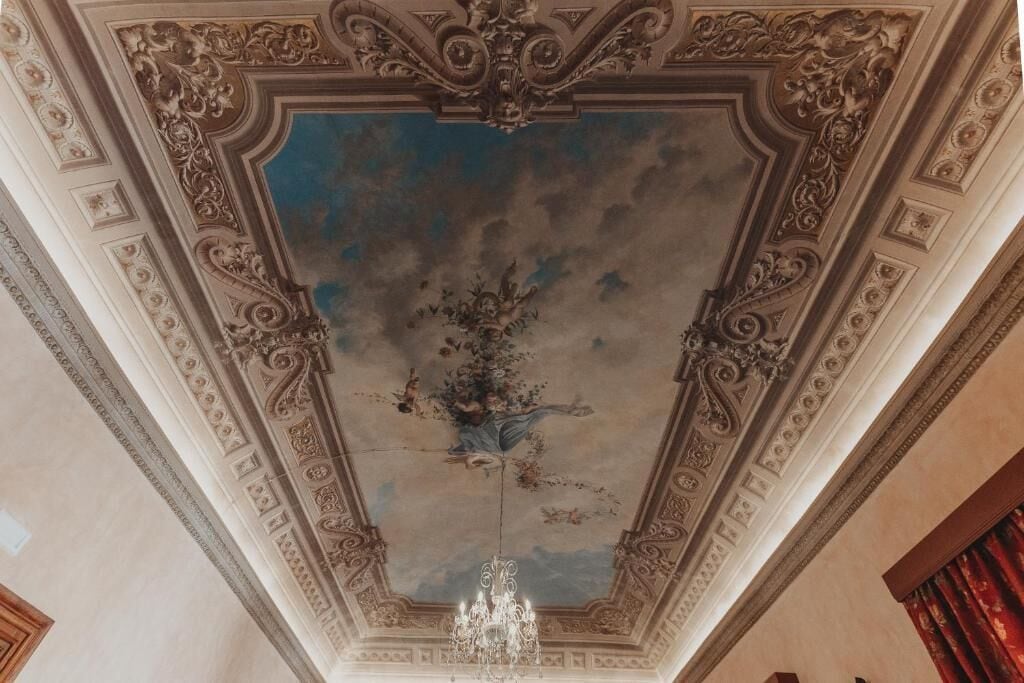 An ornate ceiling with intricate designs and a chandelier.
