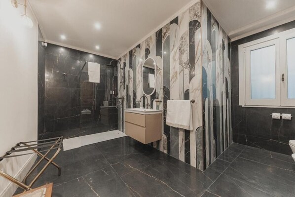 Une salle de bain moderne avec un mur en marbre, un lavabo, un miroir et des toilettes.