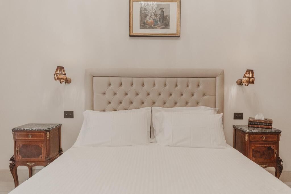 A bed with a tufted headboard, two bedside tables with lamps, and a framed picture on the wall.