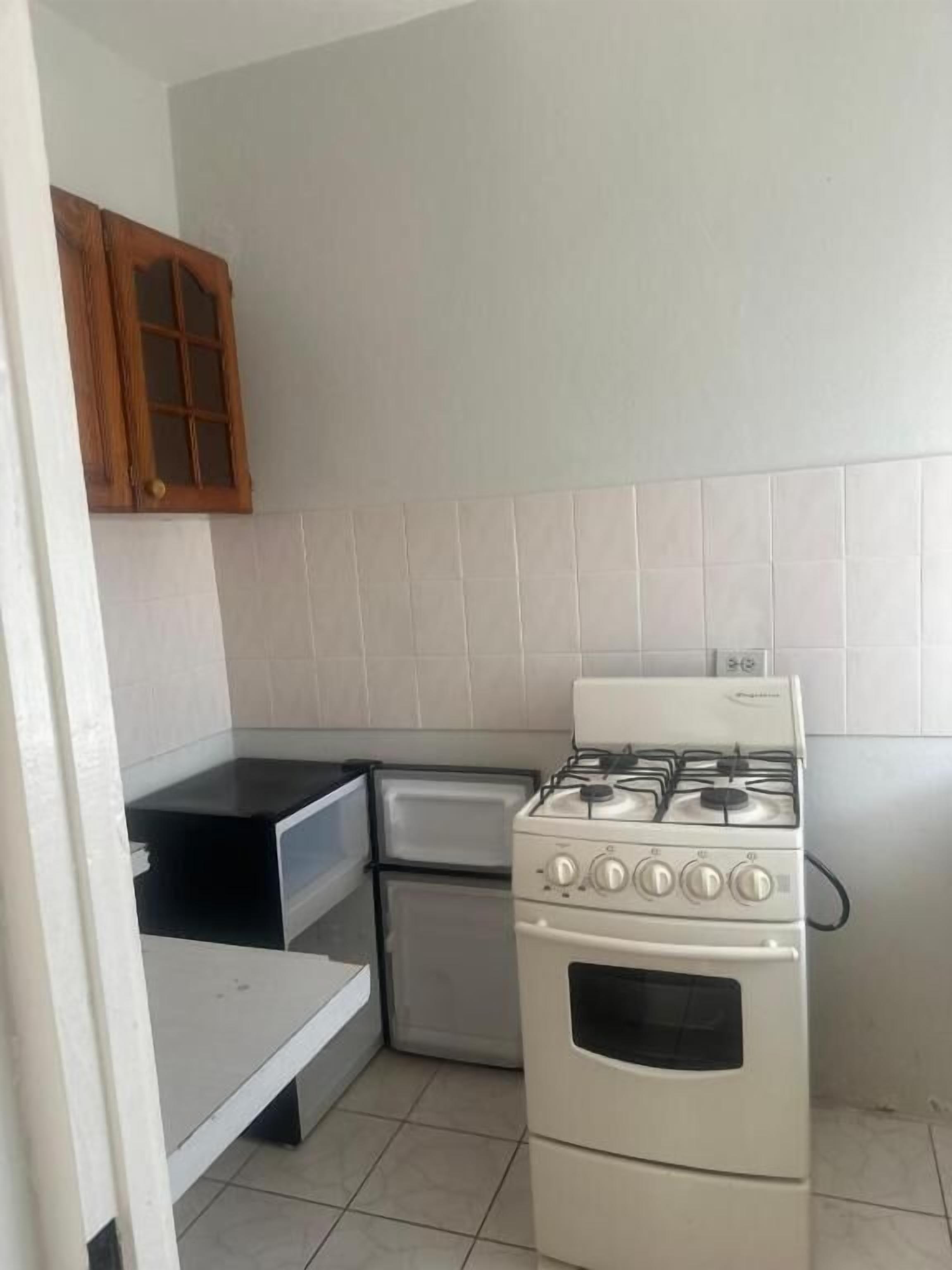A compact kitchen with a gas stove, oven, and a small refrigerator.