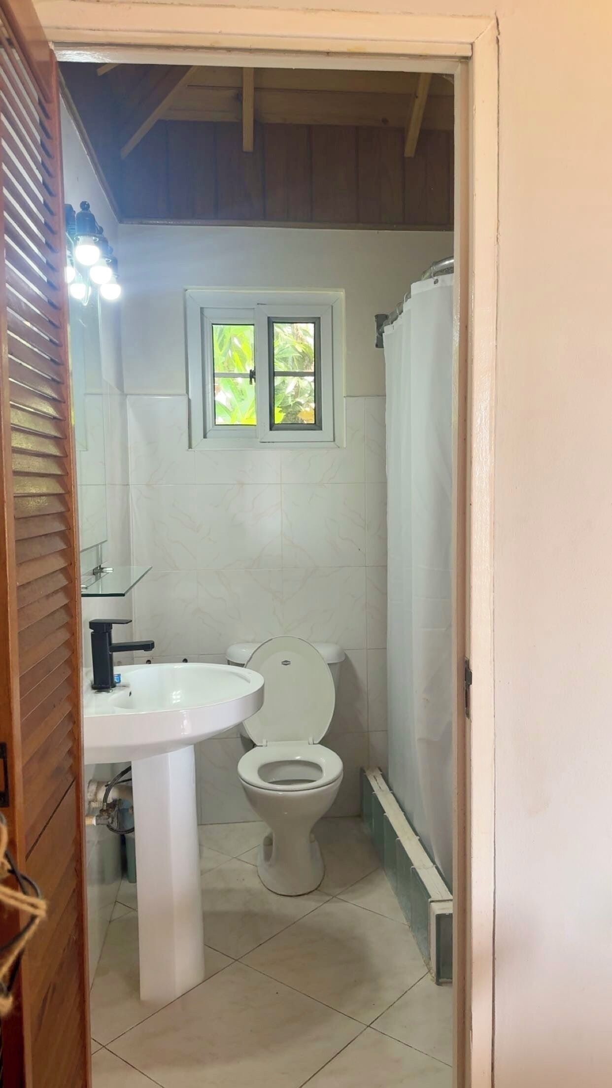 A bathroom with a toilet, sink, and window.