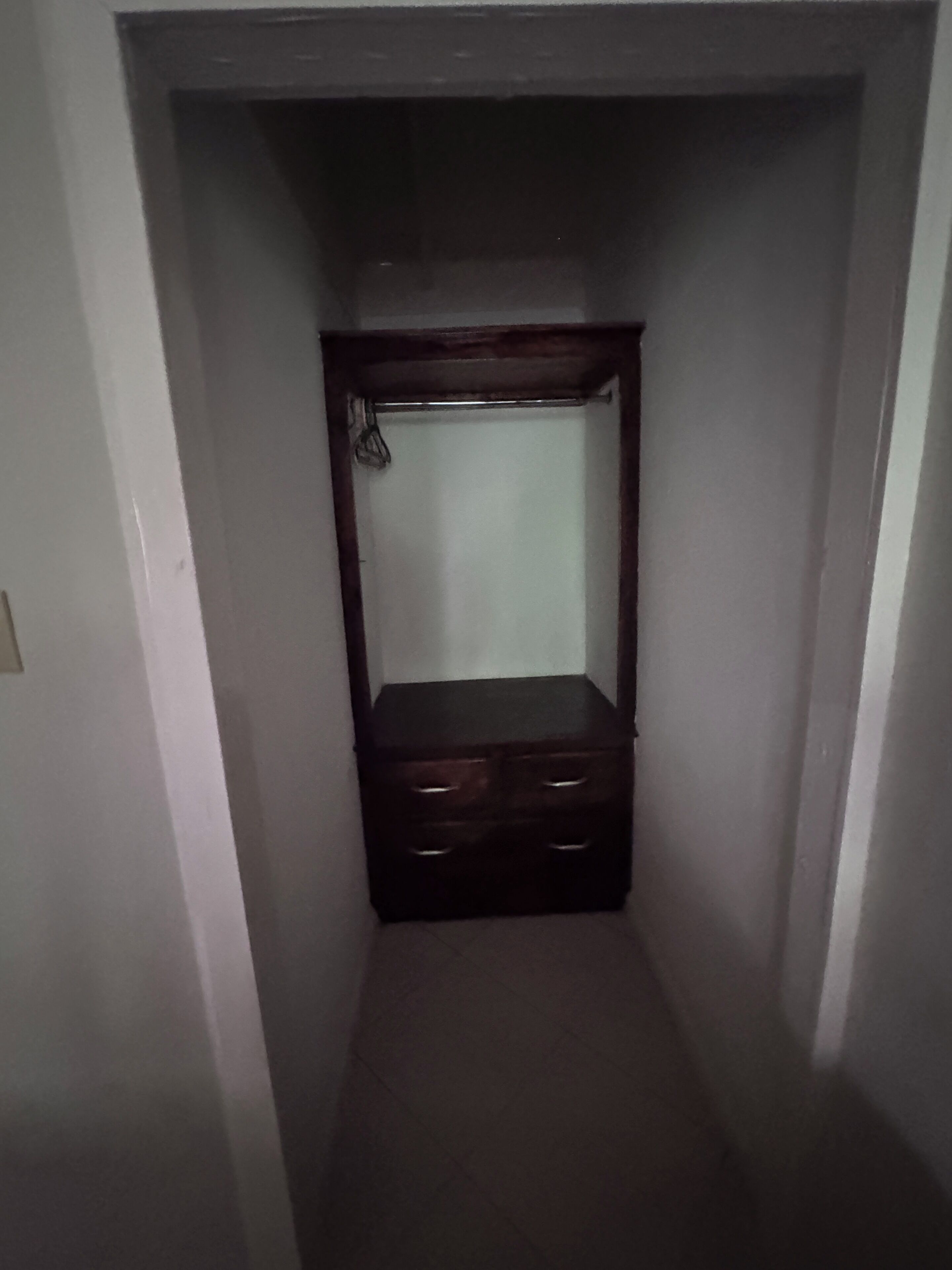 A narrow hallway with a wooden wardrobe and a mirror.