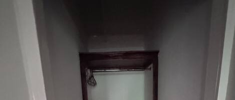 A narrow hallway with a wooden wardrobe and a mirror.