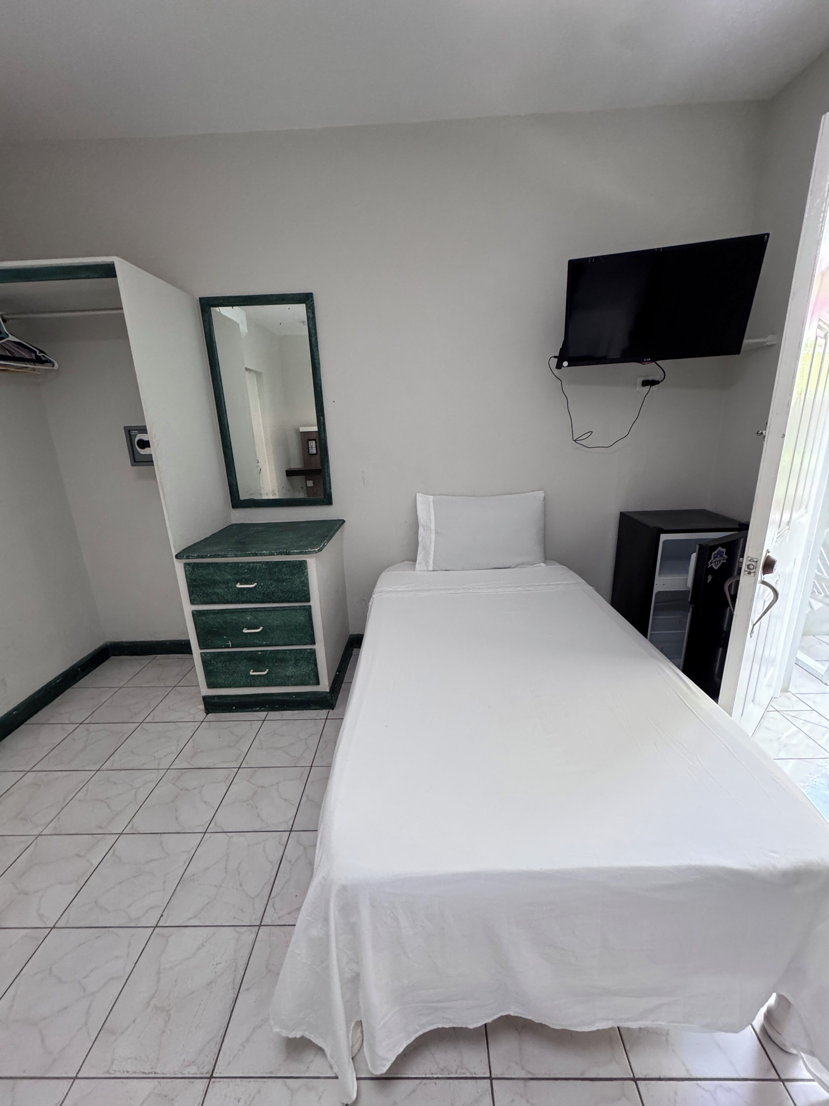 Ein Hotelzimmer mit Bett, Schminktisch, Fernseher und Kleiderschrank.