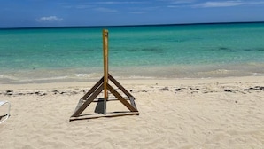 Una playa con agua turquesa cristalina y una estructura de madera sobre la arena.