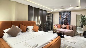 A modern bedroom with a large bed, a sofa, a fan, and a mirror. - Classic 1 bedroom apartment  (Lekki)