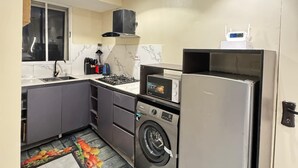 A compact kitchen with a built-in washing machine, a microwave, and a refrigerator. - Classic 1 bedroom apartment  (Lekki)