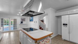 A kitchen with a white countertop, a built-in stove, and a stainless steel range hood. - La  Casona (Miami)