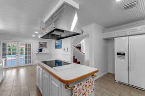 A kitchen with a white countertop, a built-in stove, and a stainless steel range hood. - La  Casona (Miami)