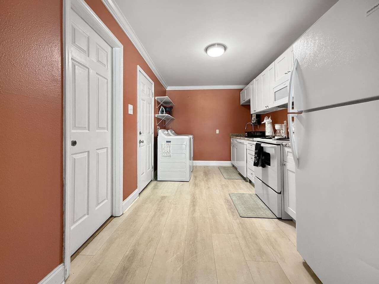 Una cocina compacta con armarios blancos, un refrigerador blanco y un microondas.