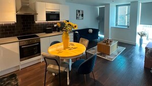 A modern kitchen with a dining area, a sofa, and a window. - London Bliss Apartment - Cozy Stay With City Views (London)
