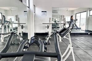 Een sportschool met trainingsapparatuur, spiegels en een loopband.