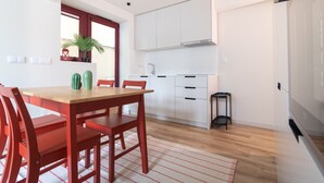 Una cocina moderna con armarios blancos, una mesa de comedor de madera y sillas rojas.