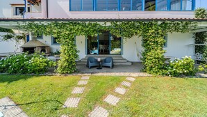 A modern house with a covered patio, a swimming pool, and a garden.
