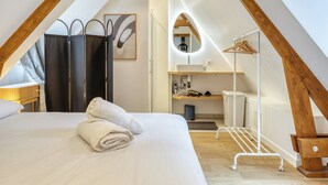Une chambre à coucher comprenant un lit, une serviette, une armoire, un miroir, un lavabo et un panier à linge.