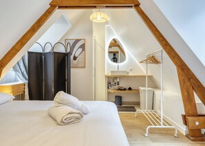 Ein Schlafzimmer mit einem Bett, einem Handtuch, einem Kleiderschrank, einem Spiegel, einem Waschbecken und einem Wäschewagen.