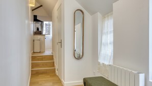 Un couloir avec un banc, un miroir et un radiateur.
