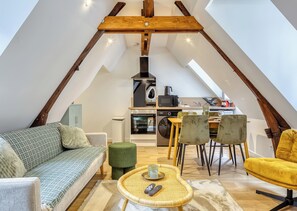 Ein Loft mit Küchenzeile, Sitzgelegenheit und Esstisch.