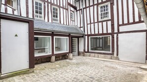Un bâtiment traditionnel à colombages, doté de grandes fenêtres et d’une cour pavée.