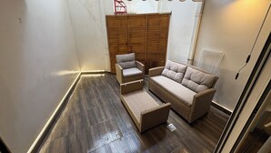 Une pièce comprenant une armoire en bois, un canapé en osier, une petite chaise et un lampadaire.