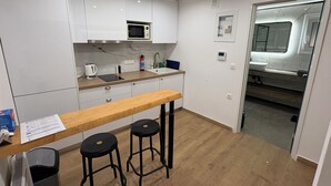Une cuisine compacte équipée d’un four à micro-ondes, d’un évier et de tabourets de bar.