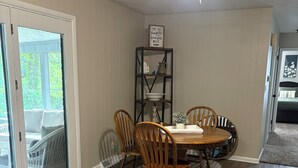Un coin repas avec une table et des chaises, un ventilateur de plafond, une bibliothèque et une vue à travers une porte vitrée.