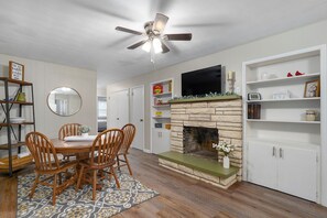 A dining area with a wooden table and chairs, a fireplace, and a television mounted above it. - Spacious 3 bedroom 3 Bath & bonus room house in marvelous Springfield with AC (Springfield)