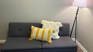 Un canapé gris foncé avec deux coussins, un lampadaire et un plancher en bois.