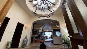 A spacious lobby with a high ceiling, a central chandelier, and a large skylight. - Oceanview Villa - The Residence at Hacienda Encantada (Cabo San Lucas)