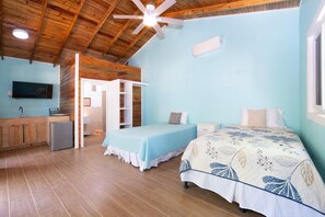 Ein Zimmer mit einem Bett, einem Schreibtisch, einem Fernseher und einem Deckenventilator.