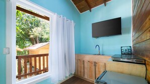 Une cuisine avec un comptoir en bois, un évier, une cuisinière et un téléviseur fixé au mur.