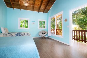 Ein Schlafzimmer mit einem Bett, einem Sessel und Blick ins Freie.