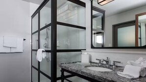 A modern bathroom with a glass shower enclosure, a granite countertop sink, and a large mirror. - Marriott Vacation Club, 1-Bedroom San Diego Suite (San Diego)