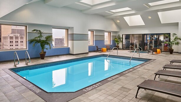 An indoor swimming pool with clear blue water, surrounded by lounge chairs and potted plants. - Marriott Vacation Club, 1-Bedroom San Diego Suite (San Diego)