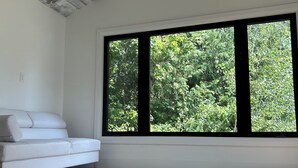 Um quarto com sofá branco, janelas amplas e teto de madeira.