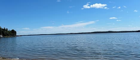 Une plage de sable fin, avec une eau calme et un ciel bleu dégagé.