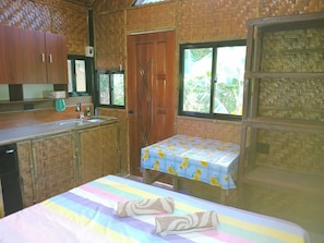 Ein Zimmer mit Bett, kleinem Tisch, Fenster und Küchenzeile.
