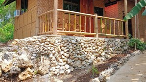 A rustic house with a stone foundation, wooden balcony, and a thatched roof.