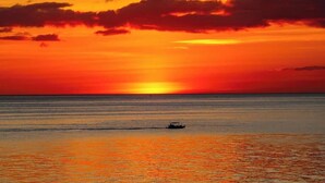 A sunset over a calm sea with a boat in the distance.