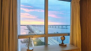A room with a large window overlooking a bridge and water during sunset. - Lake views- Luxury 2BR-2BA - Pool - Walk to Downtown (Fort Myers)