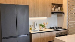 Una cocina moderna con armarios de madera, un refrigerador negro, un lavamanos y una estufa.