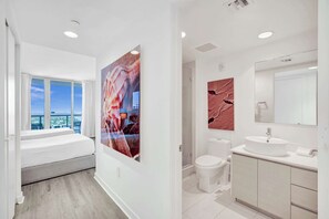 Een moderne badkamer met een grote spiegel, een wastafel en een toilet. Er is een raam met uitzicht op de stad.