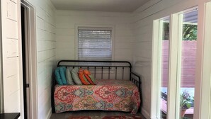 Una habitación pequeña con una cama, una ventana y una puerta.