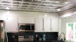 Una cocina moderna con microondas integrado, electrodomésticos de acero inoxidable y encimera negra.