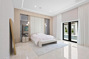 A modern bedroom with a bed, bedside tables, a mirror, and a view of the outdoors. - El Castillito (Miami)