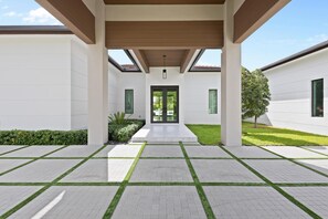 A modern building with a covered entrance, a central door, and a symmetrical design. - El Castillito (Miami)