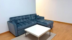 Un sofá modular con una mesa de centro blanca en una habitación con suelo de madera y paredes blancas.