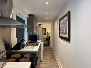 A narrow kitchen with a stove, oven, and microwave.